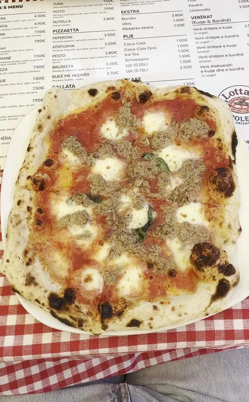 A pizza with tomato, mozzarella and basil served on top of Lotta’s printed menu
