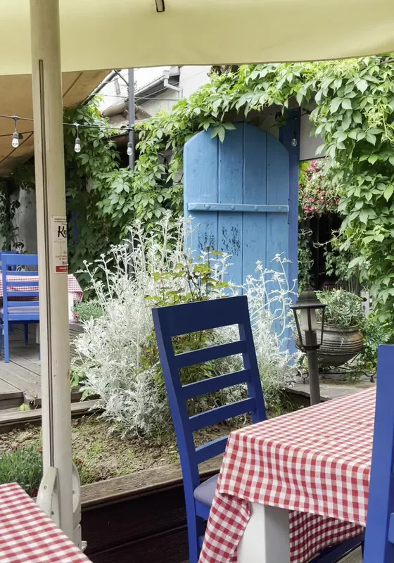 Blue chair and checked tablecloth in the garden, by an old blue door under the vines