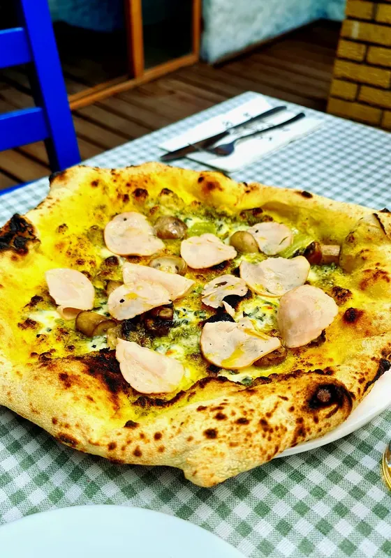 A pesto pizza with chicken on a green checked tablecloth